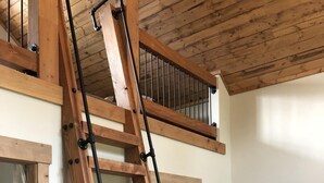 A wooden ladder in a room with a high ceiling and a window.