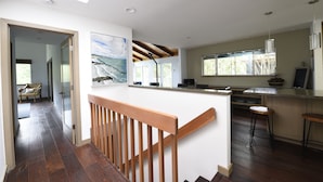 A modern kitchen with a wooden staircase, large windows, and a view of the outdoors. - Stunning Aptos Home with Treetop Views Adjacent to the Seascape Golf Course (Aptos)