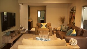 Ein Wohnzimmer mit Flachbildfernseher, zwei Sofas, einem Couchtisch und einer Treppe, die zur Küche führt.