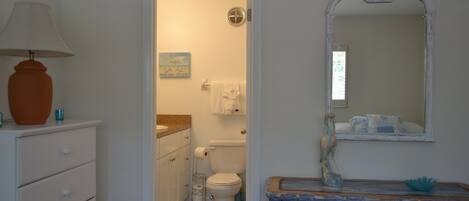 A bathroom with a white sink, a mirror, a towel rack, and a toilet.