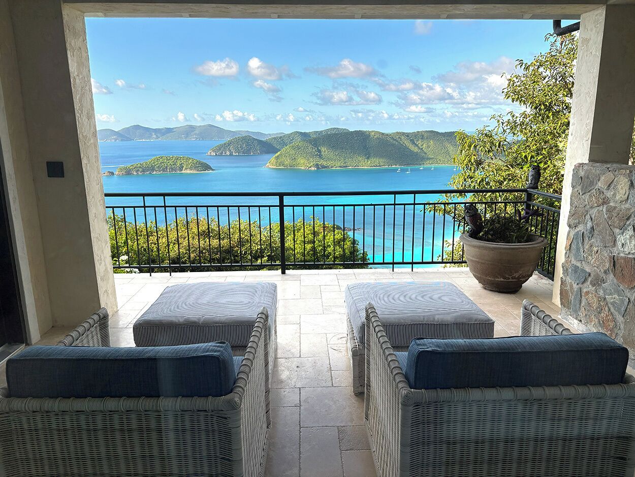 Un balcon doté de meubles en osier et offrant une vue sur un paysage côtier.
