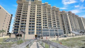 A high-rise residential building with multiple balconies, a covered walkway, and a glass facade.