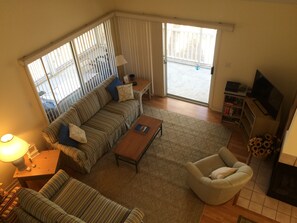 Ein Wohnzimmer mit Sofa, Sessel, Couchtisch und Fernseher.