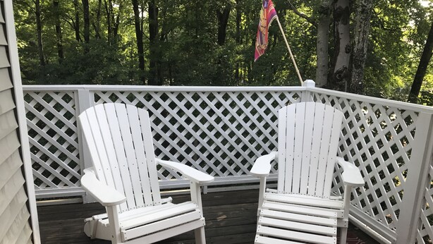 A covered deck with two white Adirondack chairs and a red patterned rug. - A family friendly beach retreat! (Ocean View)