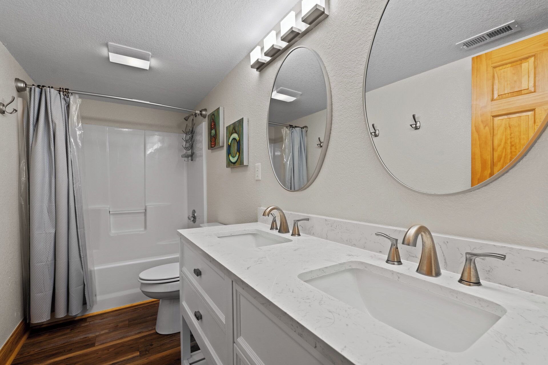 Une salle de bain moderne avec deux lavabos, des toilettes, une douche et un grand miroir.