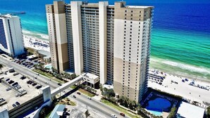 A high-rise hotel with multiple floors, a parking garage, and a beach view.
