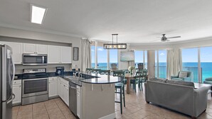 A modern kitchen with a central island, white cabinetry, and a view of the ocean.