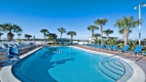 Ein Swimmingpool mit blauem Wasser, umgeben von Liegestühlen und Palmen.