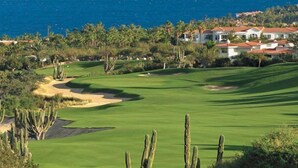 Un parcours de golf offrant une vue sur l’océan, avec une zone résidentielle en arrière-plan.