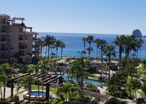 A resort with a pool, palm trees, and a view of the ocean.