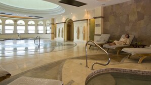 Un espace spa doté d’un grand jacuzzi circulaire, de chaises longues et d’une verrière.