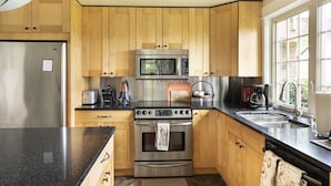 Eine moderne Küche mit Holzschränken, Edelstahlgeräten und einer schwarzen Arbeitsplatte.