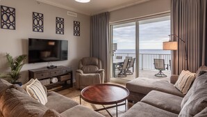 A spacious living room with a large flat-screen TV, a comfortable sofa set, a small round coffee table, and a balcony with a view of the ocean. - Ocean Ritz 4 Bedroom 4 Bath**2 King Size beds*2 Masters on water!! (Panama City Beach)