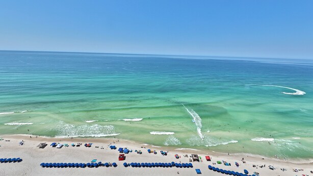 A beach with clear turquoise water, a sandy shore, and numerous umbrellas and beach chairs. - Ocean Ritz 4 Bedroom 4 Bath**2 King Size beds*2 Masters on water!! (Panama City Beach)