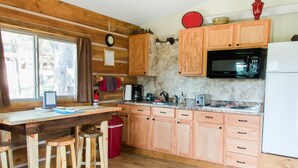 A kitchen with wooden cabinets, a microwave, a coffee maker, and a red trash bin.