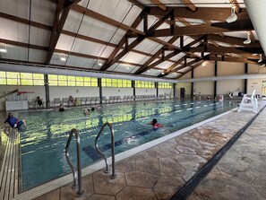 Una piscina interior con carriles delimitados, techo de madera y suelo de piedra.