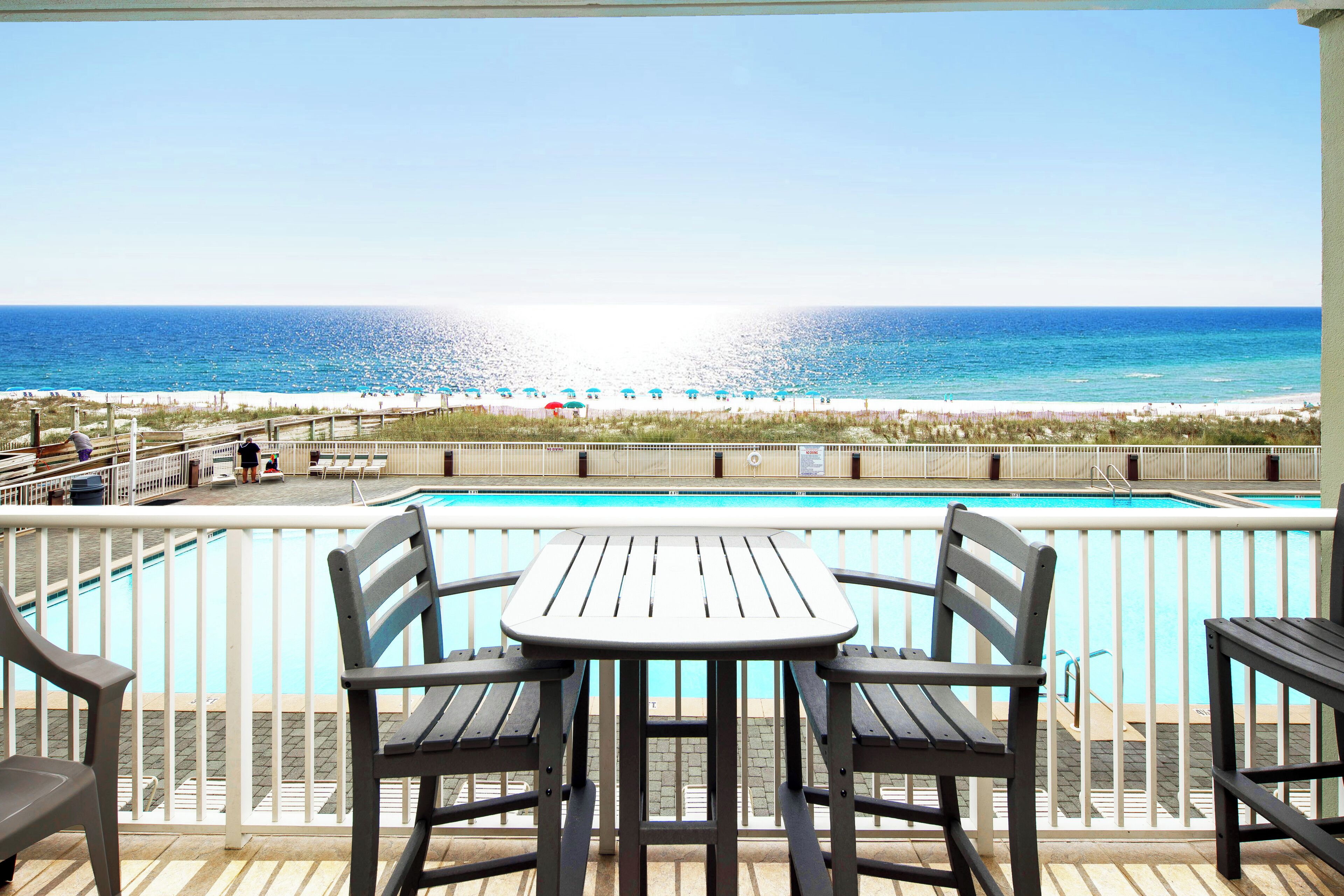 A poolside area with a view of the beach and ocean.