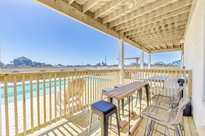 A wooden deck with a pool, a table, and chairs, overlooking a residential area. - Semi-Oceanfront Rodanthe Home w/ Pool, Hot Tub, Elevator, Game and Media Rooms (Rodanthe)