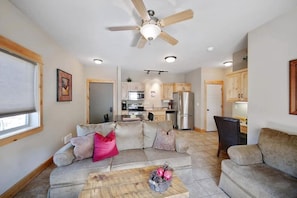 A living room with a sofa, coffee table, and a ceiling fan.