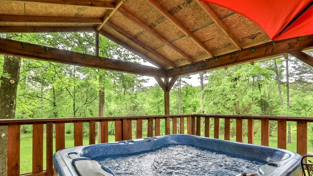 Een hottub op een houten terras met uitzicht op een bos.