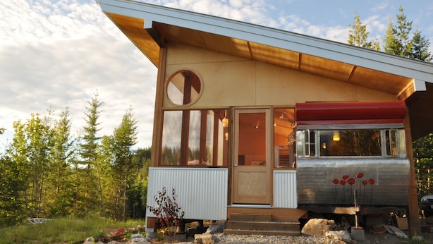 Une cabane moderne dotée d’une grande fenêtre, d’une porte et d’un petit espace porche.