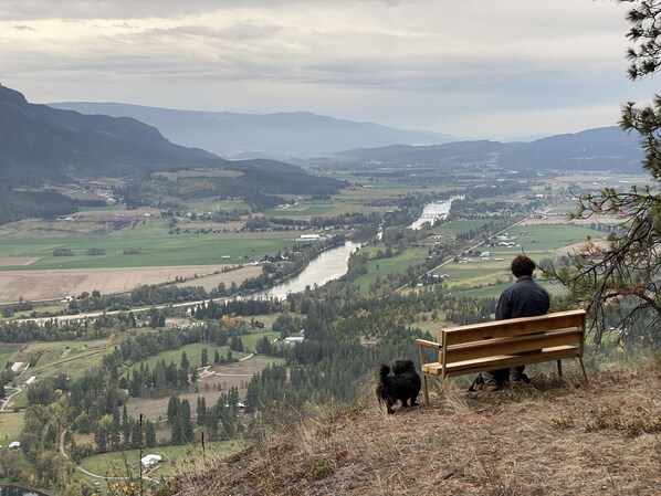 Un banco con vista a un valle, con un río, campos y montañas.