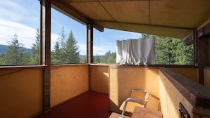 Une pièce avec un plafond en bois, une fenêtre avec un rideau, un bureau en bois et une chaise.