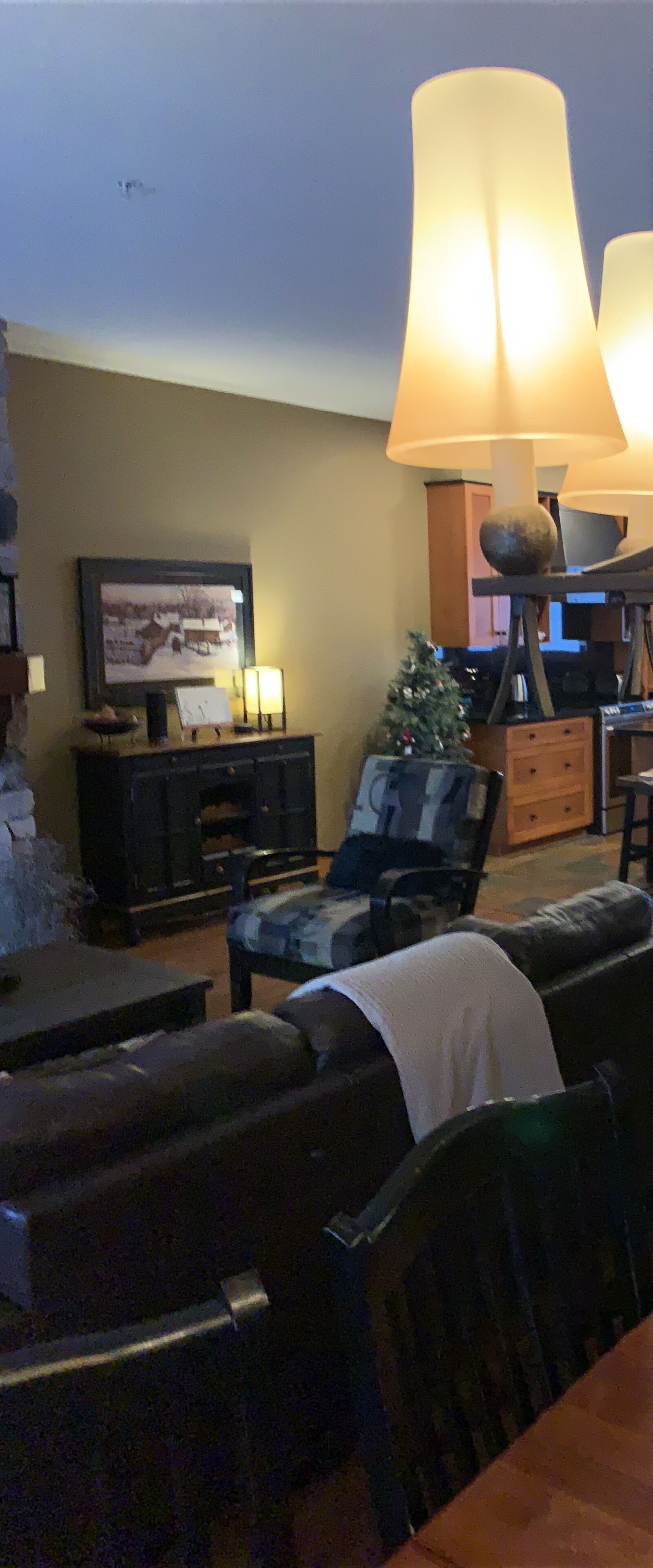A living room with a large lamp, a television, a Christmas tree, and a fireplace.