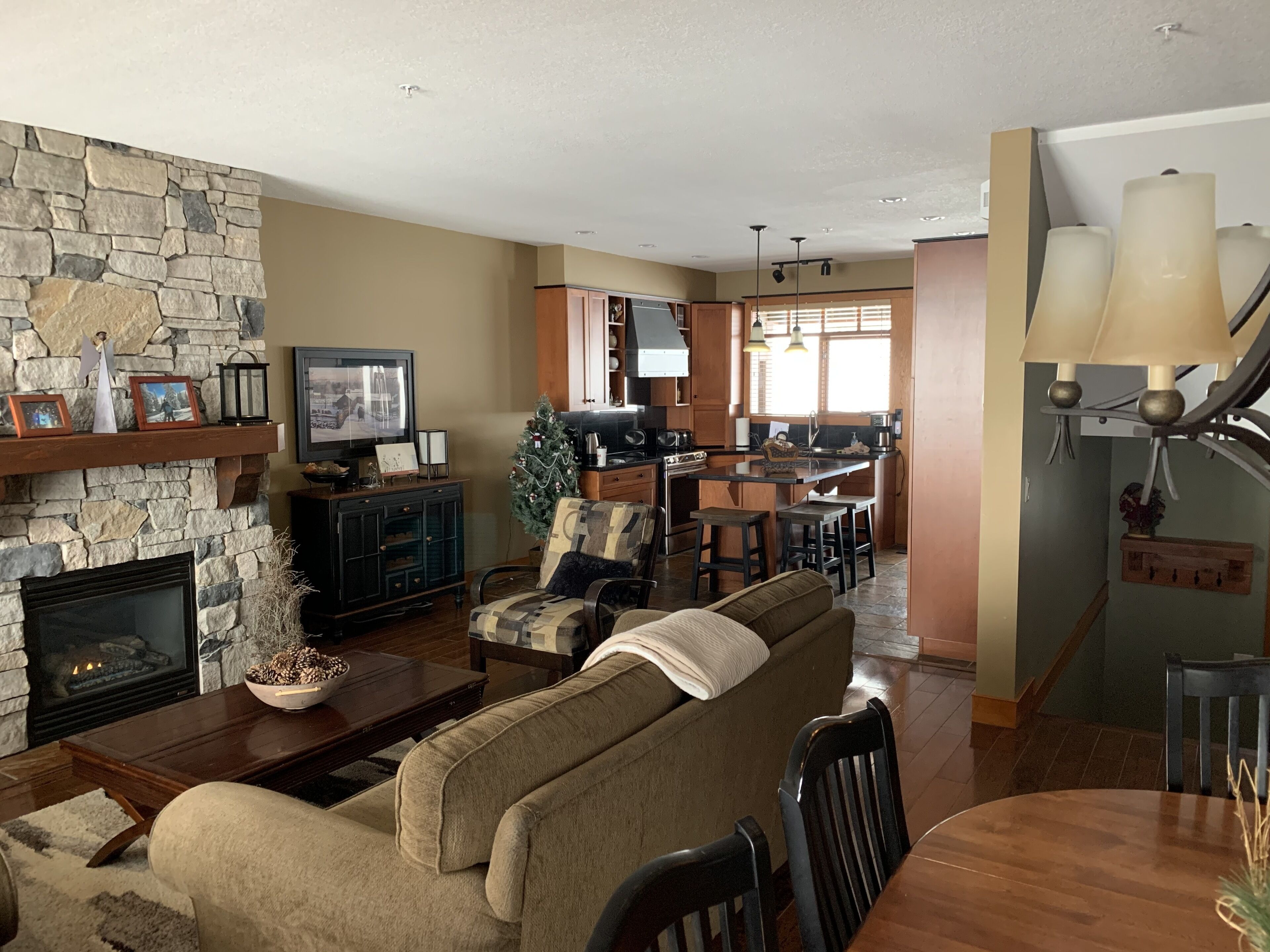 A living room with a stone fireplace, a television, and a Christmas tree.