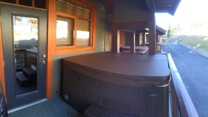 Un área de hidromasaje con terraza de madera, zona de estar cubierta y vistas a un paisaje montañoso.