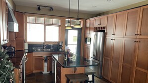 Una cocina moderna con armarios de madera, un refrigerador de acero inoxidable, un horno empotrado y una isla grande con taburetes de bar.