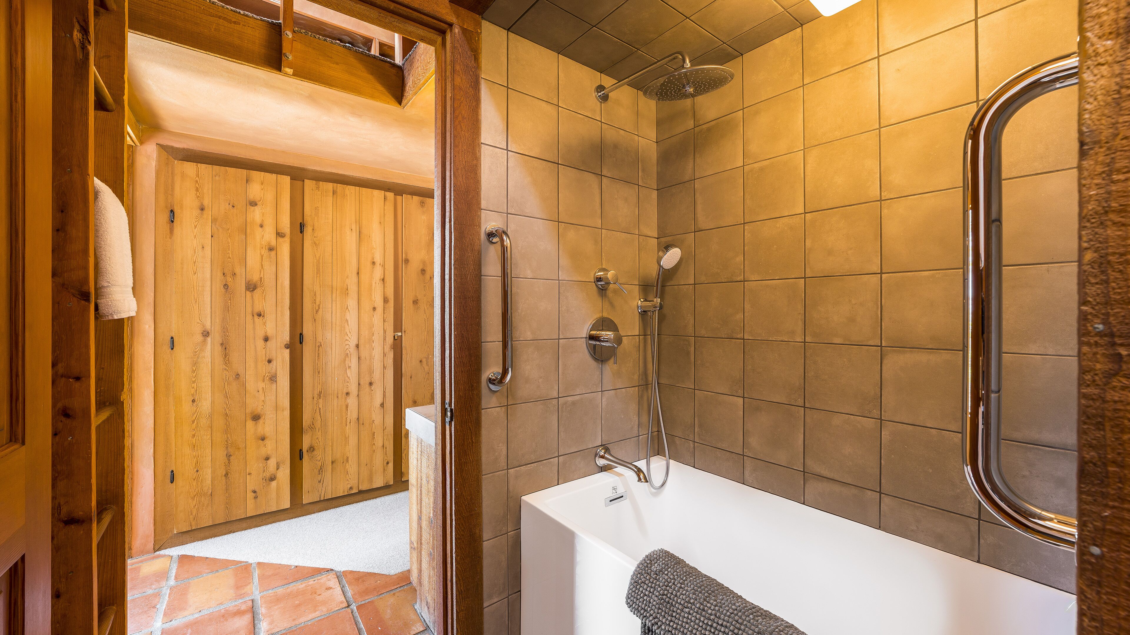 Ein Badezimmer mit Badewanne, Dusche und Holztür.
