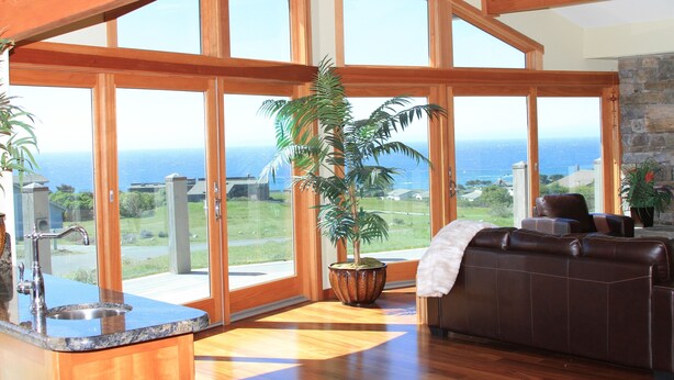 Amplia sala de estar con ventanas grandes, cocina con lavamanos y chimenea de piedra.
