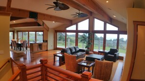 Amplia sala de estar con techo alto, ventanas grandes y vistas al exterior.