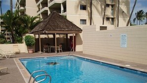 Une piscine avec des chaises longues et un kiosque.