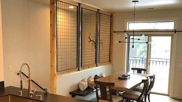 Una cocina con una isla central, armarios de madera, un lavaplatos de acero inoxidable y una zona de comedor con mesa y sillas.