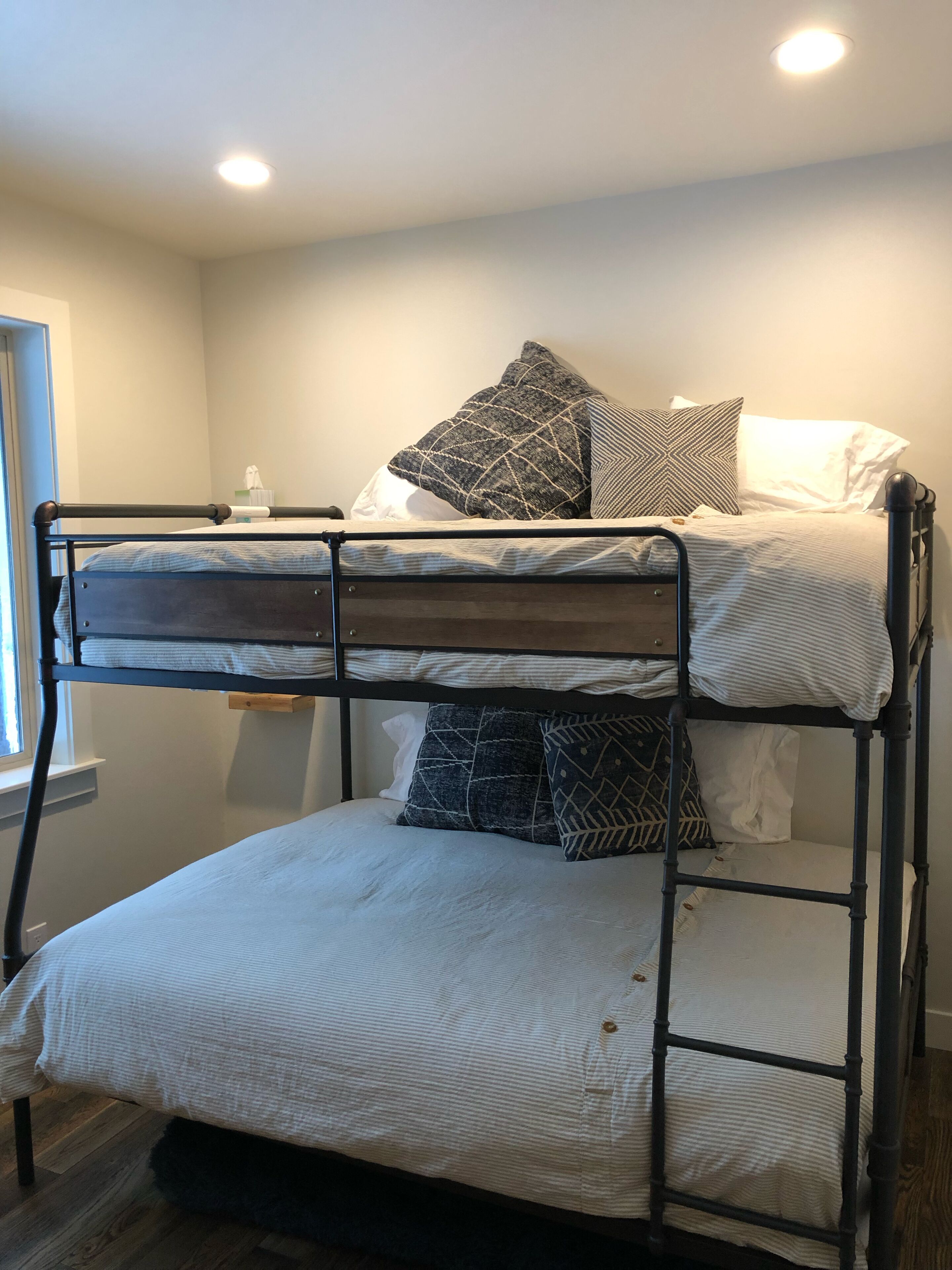A bunk bed with two levels, each with a mattress and pillows.