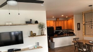 Una cocina moderna con armarios de madera, una isla central y una zona de comedor con sillas de madera.