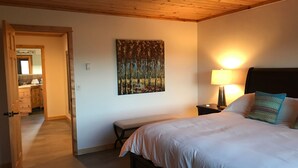 Un dormitorio con cama, mesita de noche, lámpara y un cuadro en la pared.
