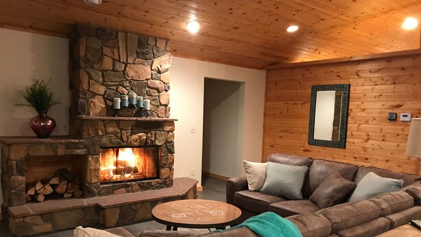 Un salón acogedor con chimenea de piedra, sofá de cuero y una mesa de centro redonda de madera.