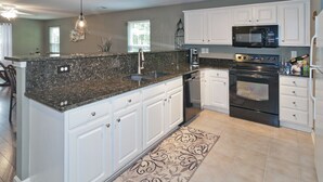 A modern kitchen with white cabinets, granite countertops, a built-in oven, and a microwave.