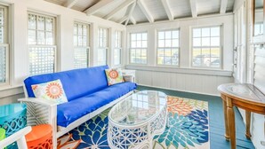 A bright, open room with a blue sofa, a glass coffee table, and a patterned rug. - "The Carousel House" - Ocean Park - Featured in New York Times (Oak Bluffs)