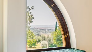 A bedroom with a curved window overlooking a landscape. - Villa with pool in the middle of Maremma (Magliano)