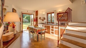 A cozy kitchen with a dining table, chairs, and a staircase leading to an upper level. - Villa with pool in the middle of Maremma (Magliano)