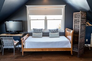 A bedroom with a bed, a television, a desk, and a window.