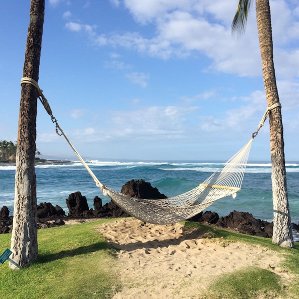 A hammock tied between two trees on a sandy beach with ocean waves in the background. - Luxury accommodations, discounted golf and beautiful sunsets year round. (Waikoloa Village)