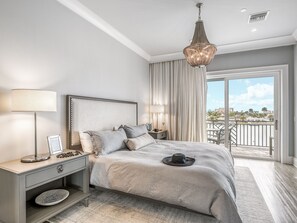 Ein Schlafzimmer mit einem großen Bett, zwei Nachttischen, einer Hängeleuchte und Blick auf die Stadt vom Balkon aus.