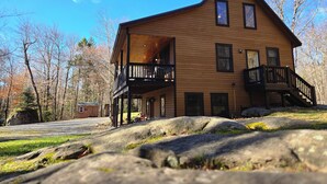 Een houten chalet met twee verdiepingen en een balkon op de bovenverdieping, gelegen in een natuurlijke omgeving.
