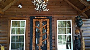 A wooden cabin with a large wooden door, two windows, a chandelier, and a bear sculpture. - Tree House Lodge-Real Log Mountain Paradise (Hiawassee)