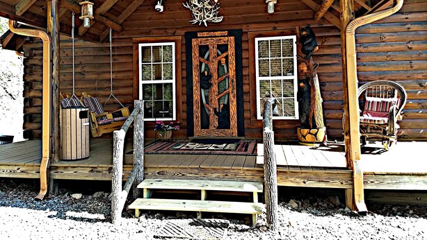A wooden cabin with a porch, a welcome sign, and a bear sculpture. - Tree House Lodge-Real Log Mountain Paradise (Hiawassee)